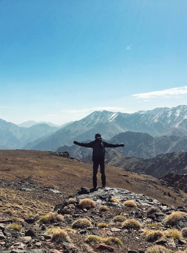a person standing on a rocky hill with mountains in the background