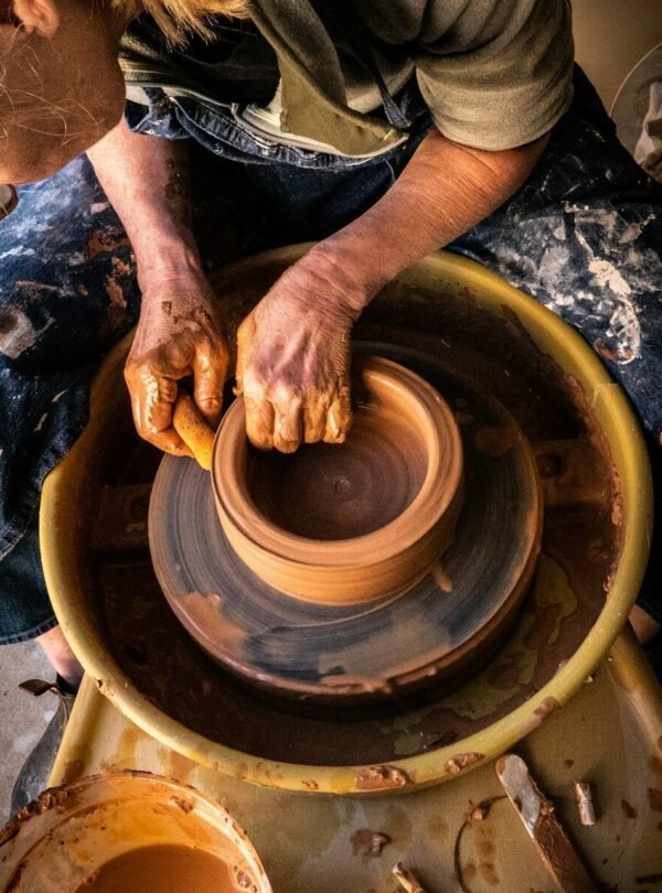 person in blue denim jeans making clay pot