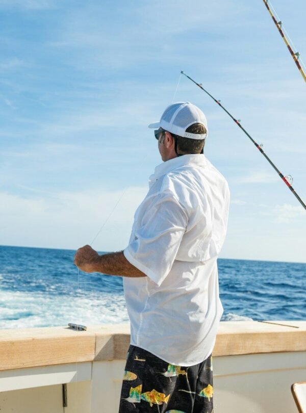 man standing on boat near fishing rods