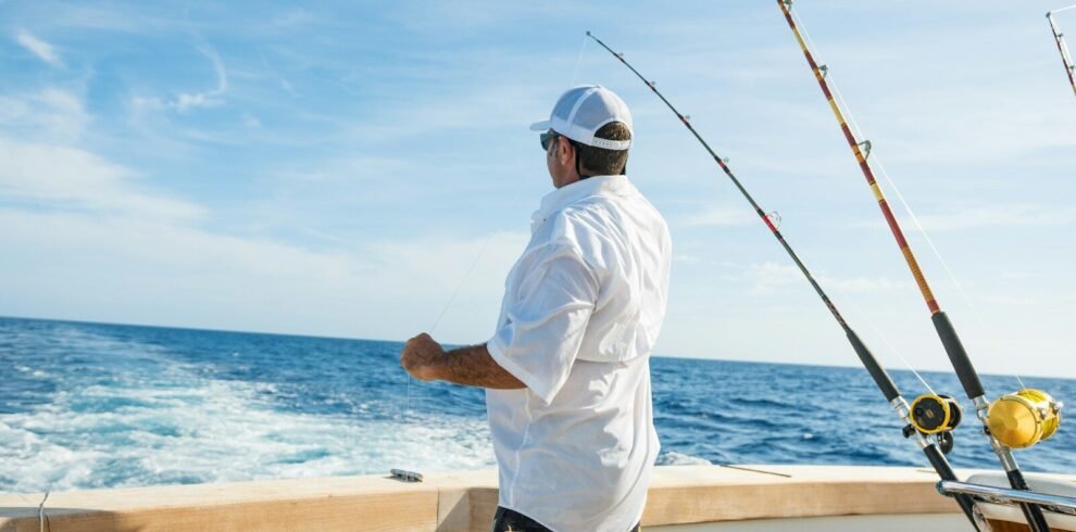 man standing on boat near fishing rods