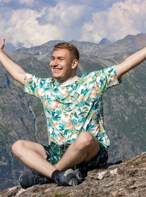 a man sitting on top of a mountain with his arms wide open