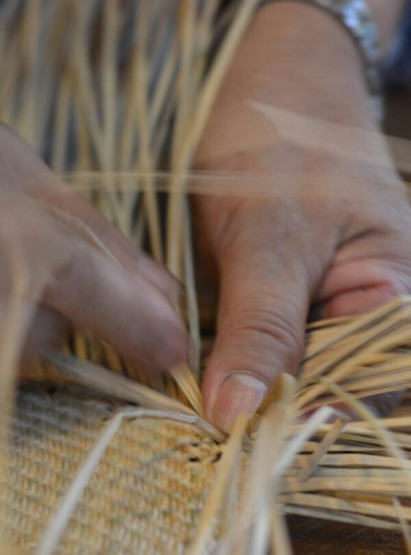 person woving beige straw