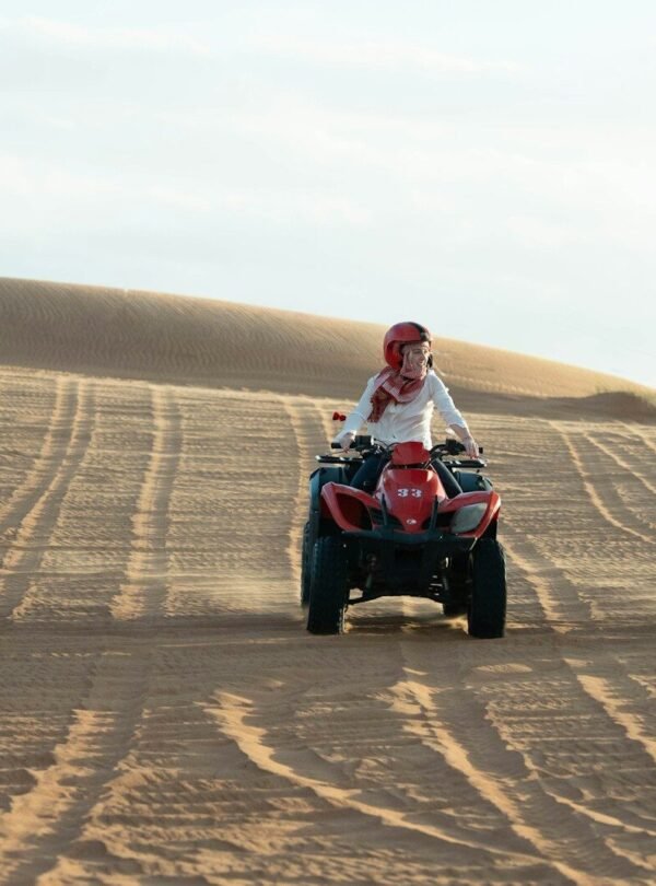 Three people riding atvs on sand dunes