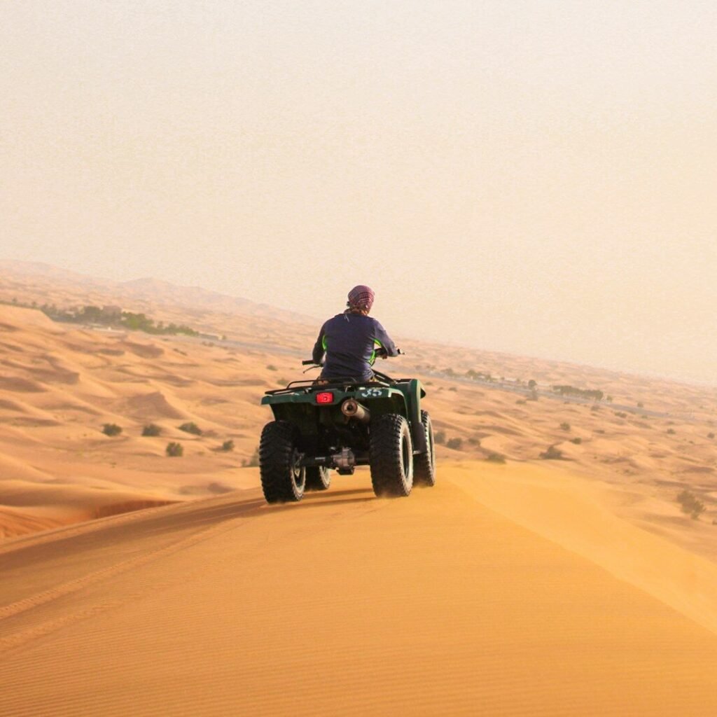 man riding black atv on brown sand during daytime