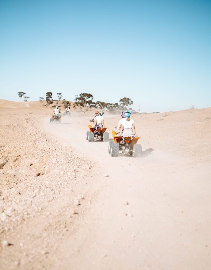 people riding motorcycle on brown sand during daytime