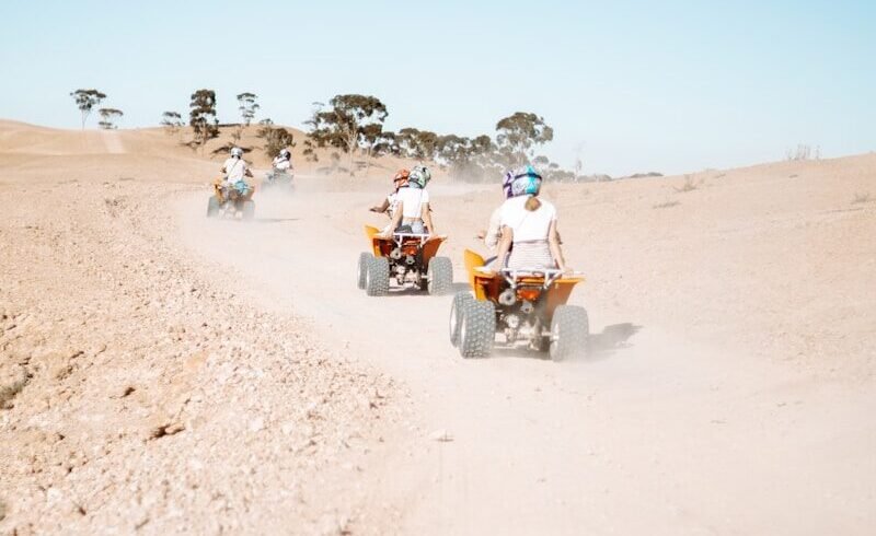 people riding motorcycle on brown sand during daytime