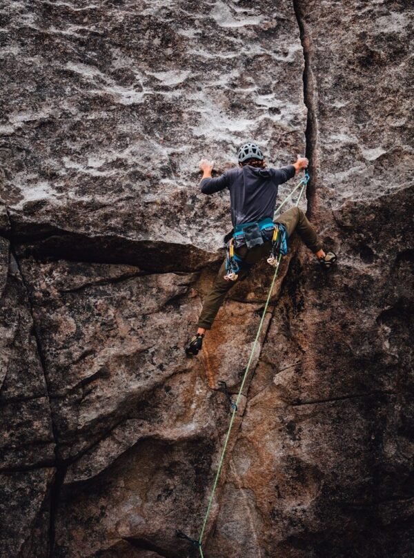 man in blue t-shirt climbing on brown rock during daytime
