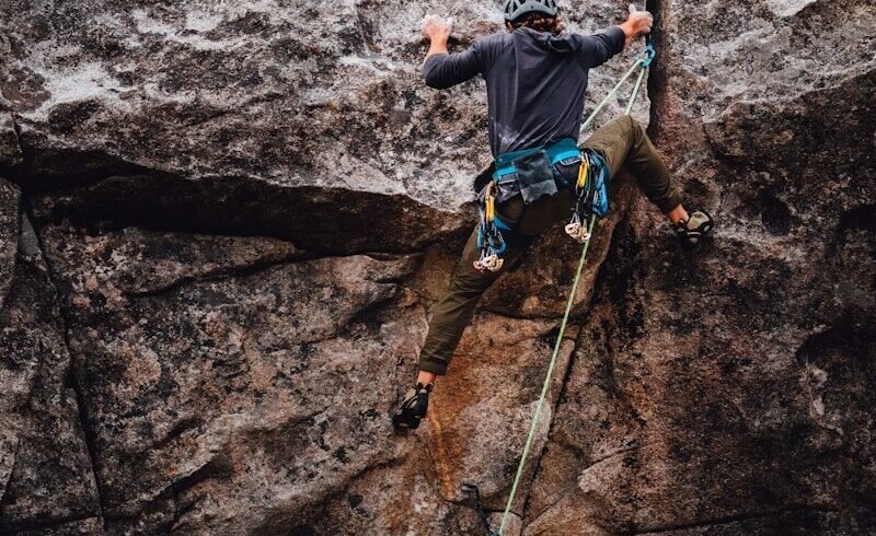 man in blue t-shirt climbing on brown rock during daytime