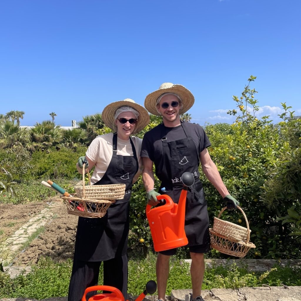 Travelers wearing straw hats holding watering cans and woven baskets during an eco-farming experience