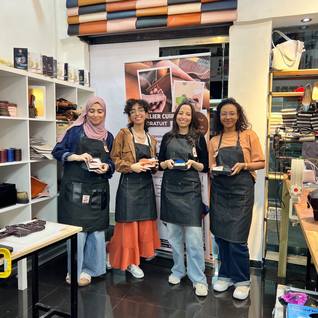Four female participants holding their finished handmade leather goods at a workshop
