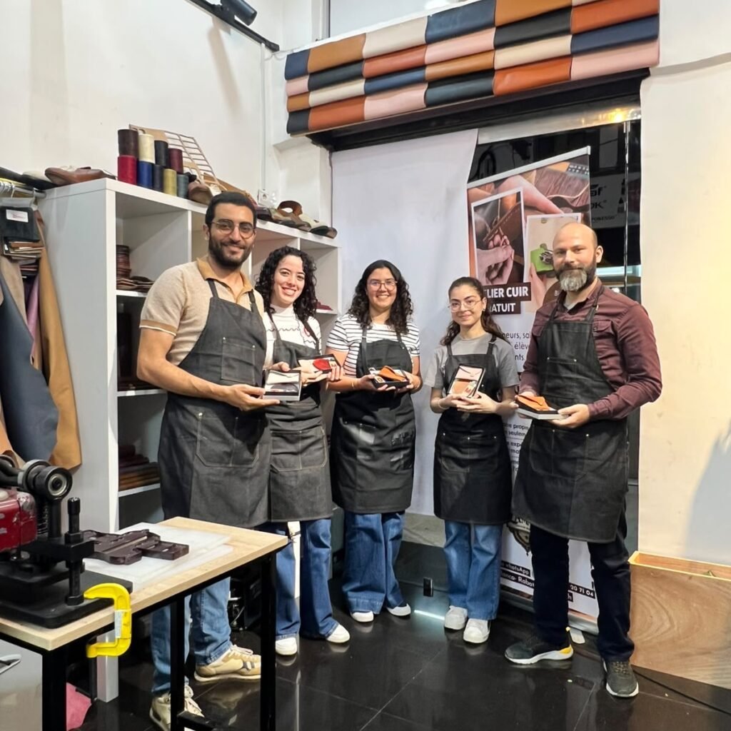 Group of participants wearing aprons and displaying small leather craft projects