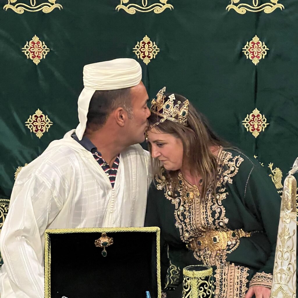 A groom traveler kissing the forehead of his bride during a traditional Moroccan wedding ceremony