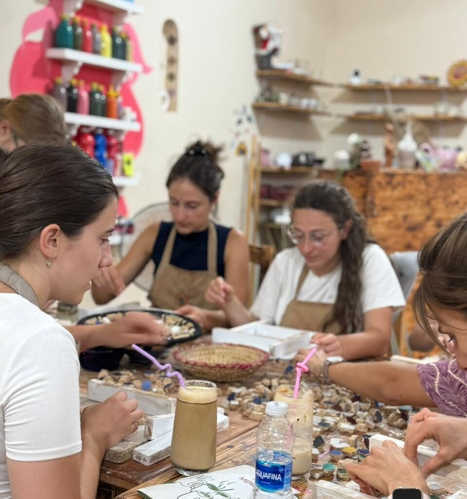 Group of travelers assembling intricate Moroccan zellij tile mosaics in a craft class