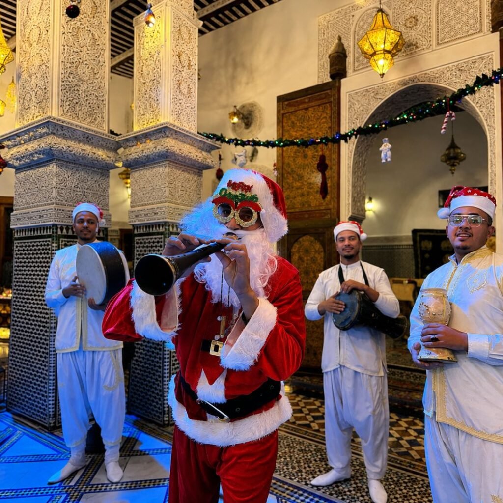 Performer in a Santa Claus suit standing beside musicians playing traditional Moroccan instruments during a festive celebration