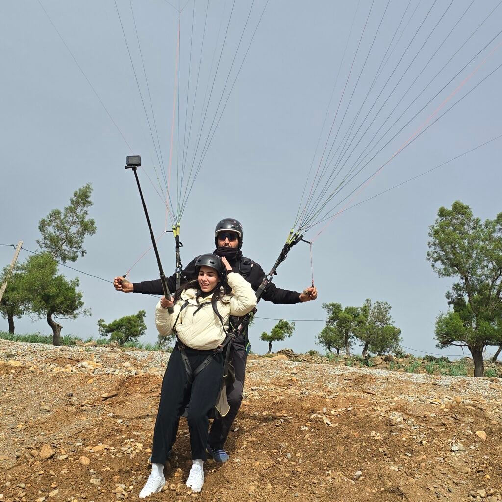 Paragliding pilot and passenger on a rocky hill with an open canopy