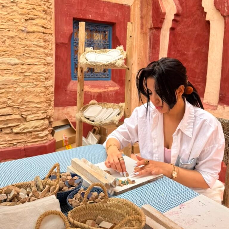 Female traveler creating a traditional zellij mosaic art piece at a table in a workshop