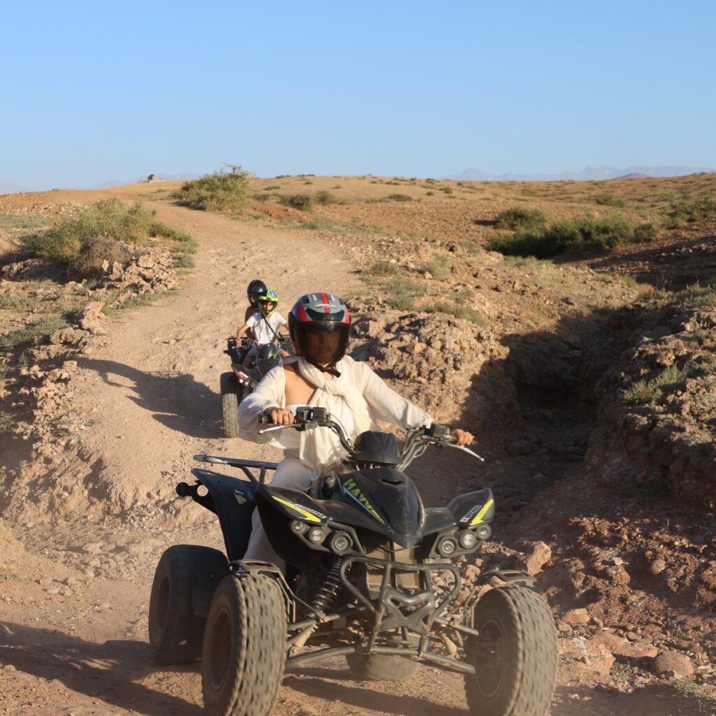 Participant wearing a helmet while riding a quad bike on an outdoor desert adventure trail
