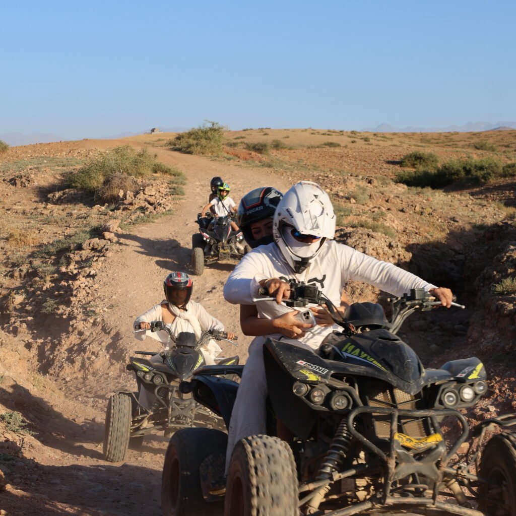 Group of adventurers driving quad bikes in a line across an open desert landscape