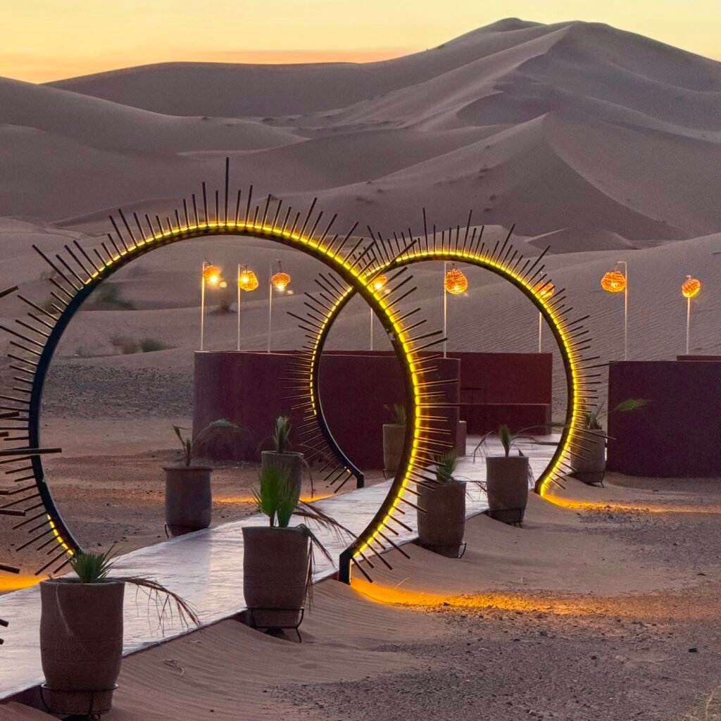Desert camp pathway with illuminated archways welcoming travelers at dusk in the Sahara sand dunes
