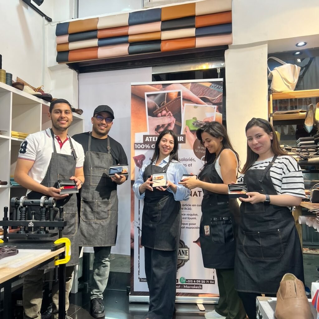 Five participants smiling while showing off their finished leather accessories in a studio