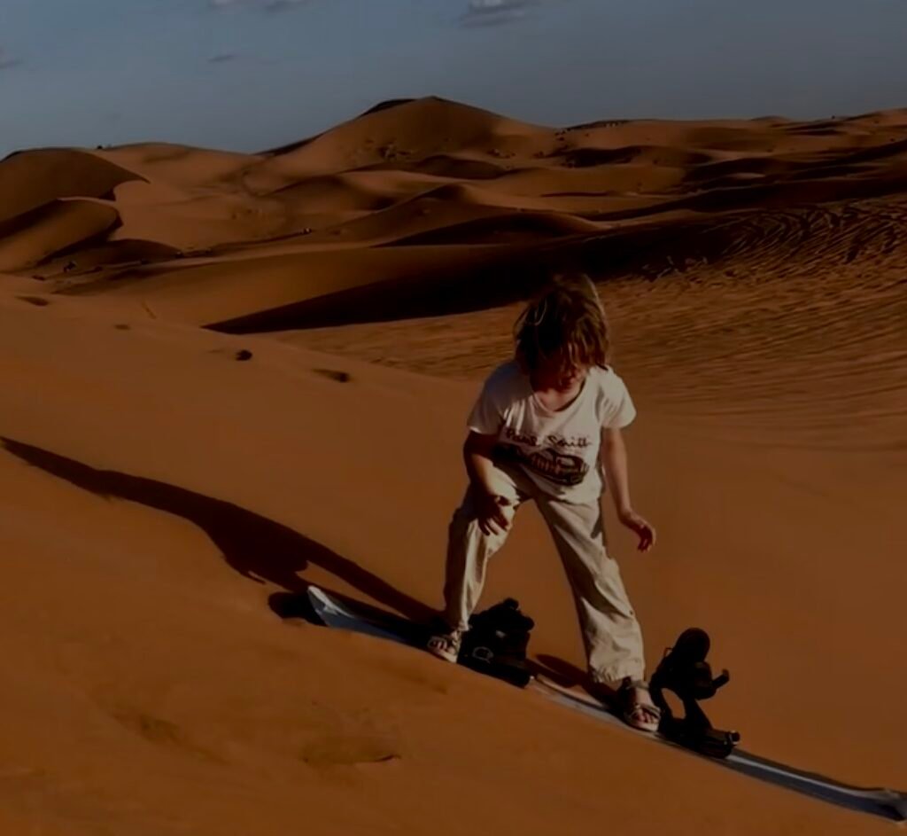 Person preparing to sandboard down golden desert sand dunes
