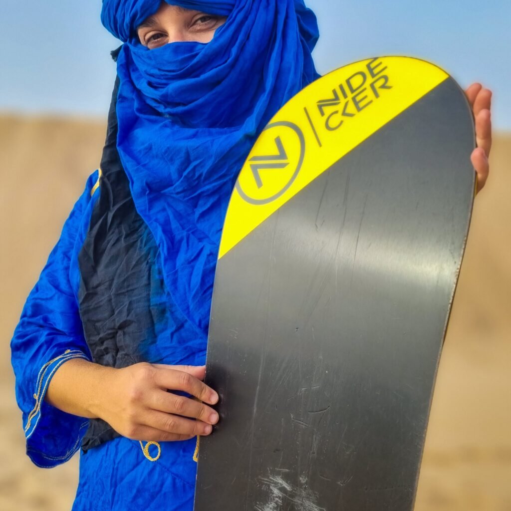 Female traveler holding a sandboard on a Sahara desert dune tour