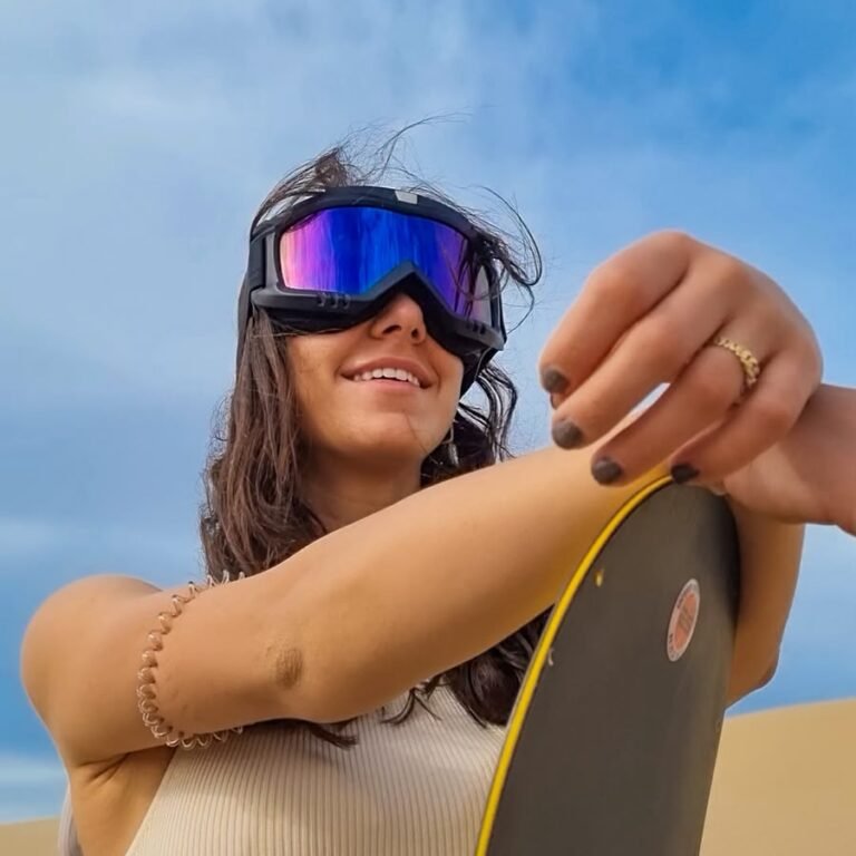 Female traveler posing with a sandboard on a desert dune during a Sahara sandboarding tour