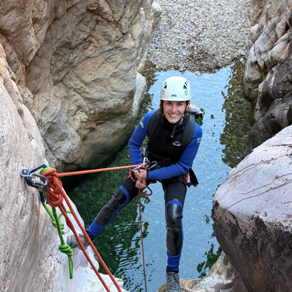 Female traveler smiling while preparing to rappel down a narrow canyon rock face in Morocco