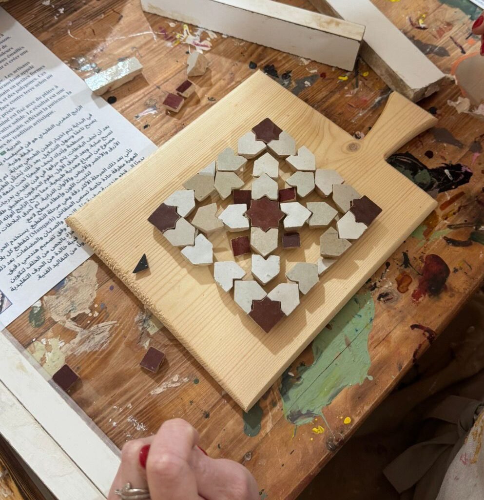 Moroccan zellij tile mosaic geometric pattern being laid out on a wooden board