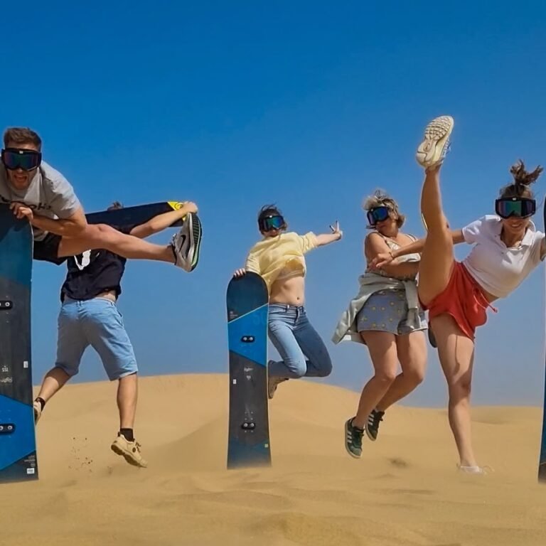 Group of adventurous travelers posing with sandboards during a Sahara desert sandboarding excursion