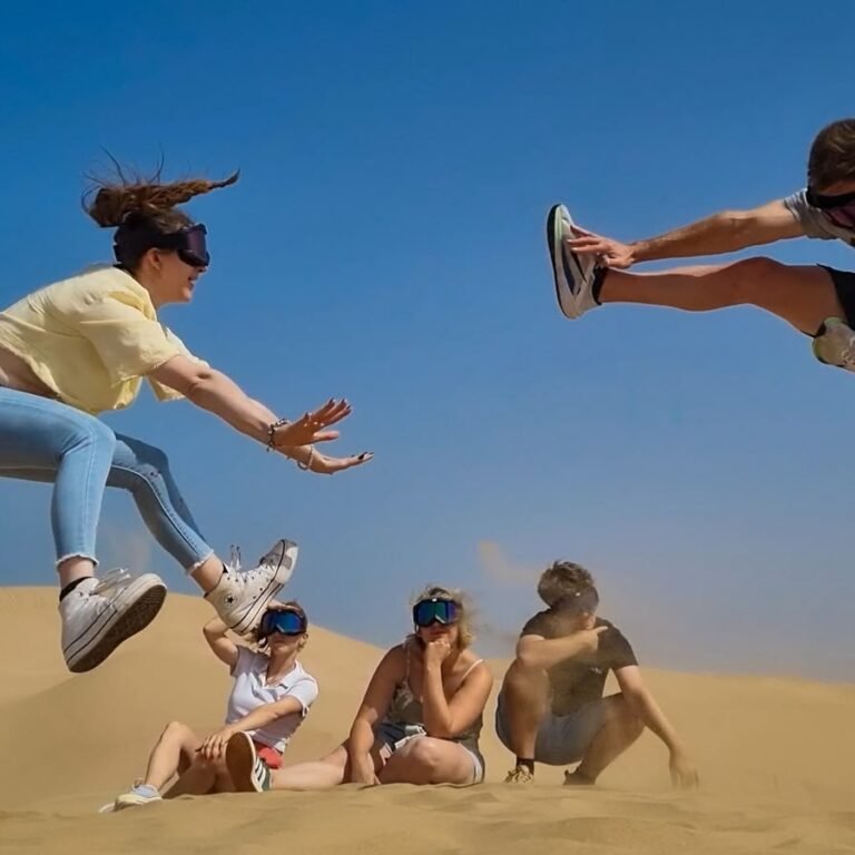 Group of energetic travelers jumping in mid-air during a Sahara desert sandboarding excursion