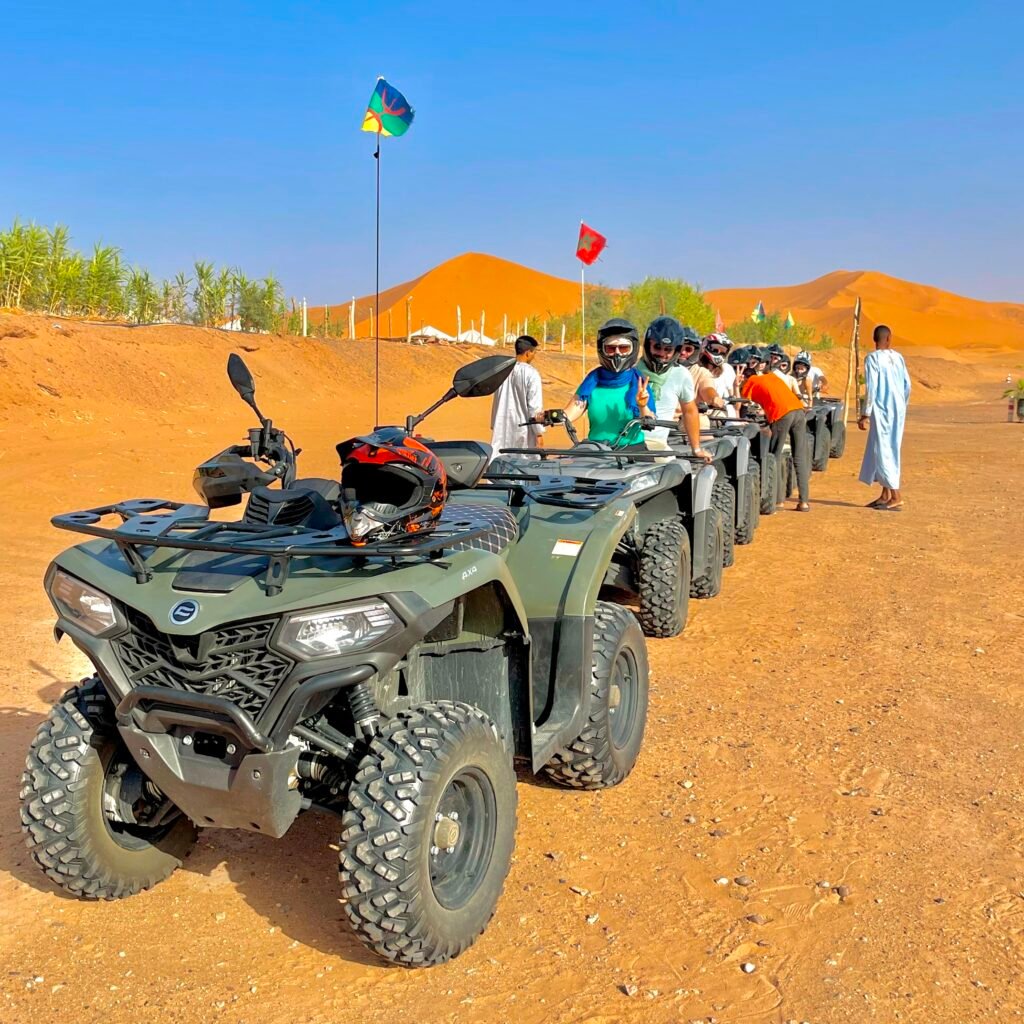 Group of travelers sitting on quad bikes preparing for a guided Sahara desert tour