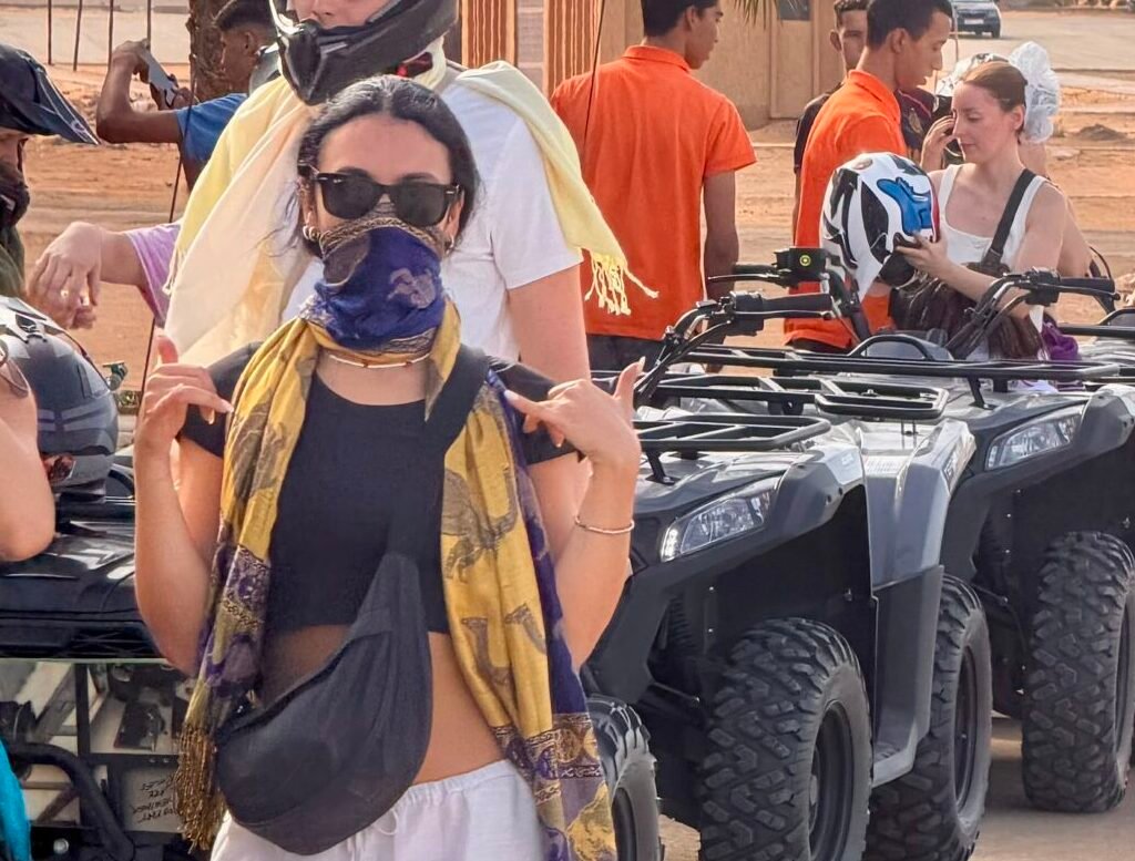 Group of travelers wearing helmets and scarves getting ready for a quad biking tour in the desert
