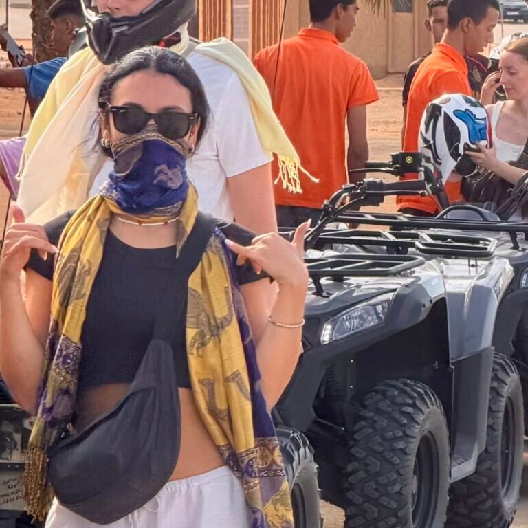 Group of travelers wearing helmets and scarves getting ready for a quad biking tour in the desert