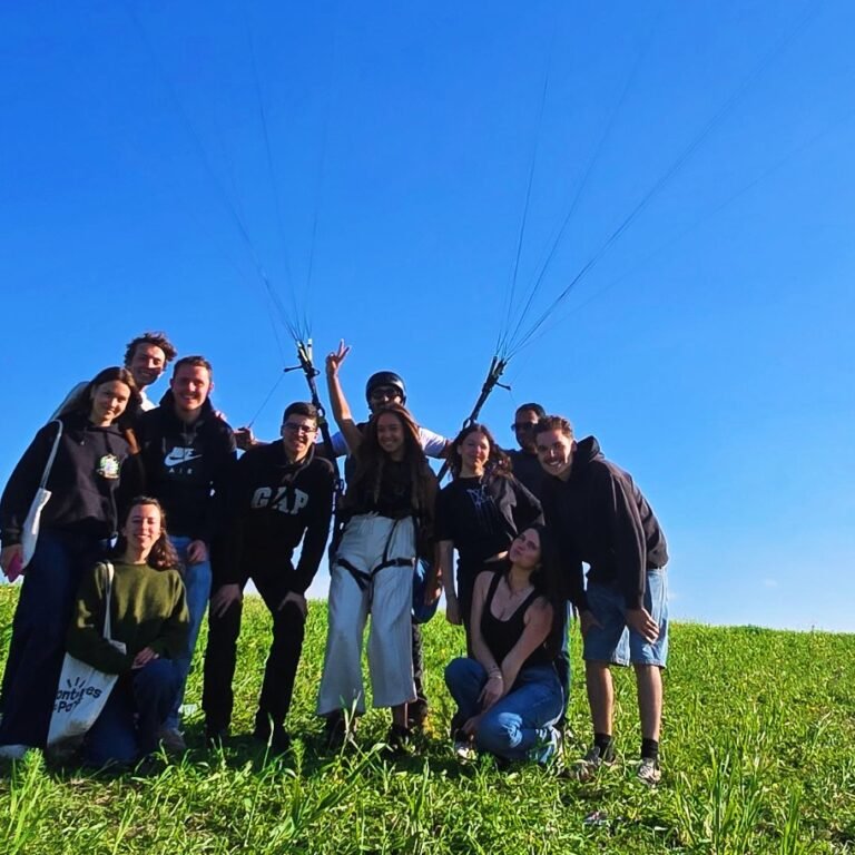Group of tour travelers posing beneath an open green paraglider canopy