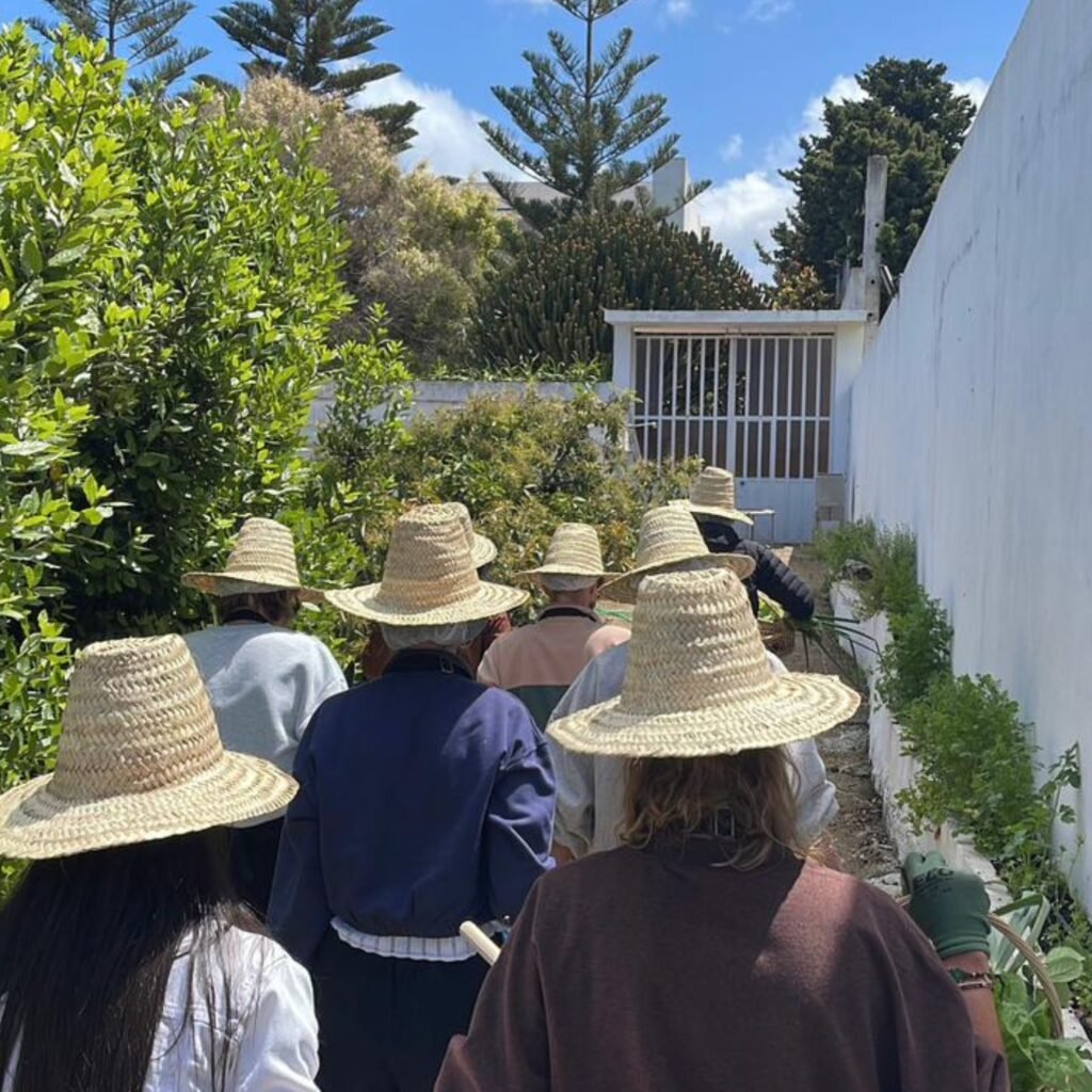 Group tour travelers wearing traditional straw sun hats walking through a lush garden