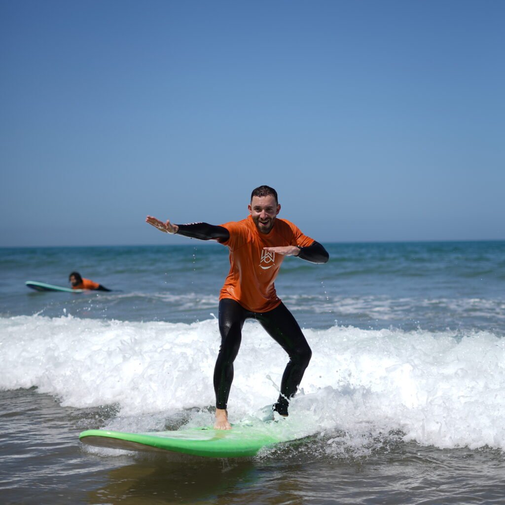 Male surfer balancing on a bright green surfboard while catching a wave