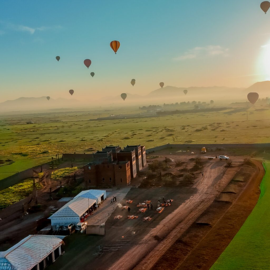 Panoramic view of hot air balloons flying over Moroccan landscape at sunrise