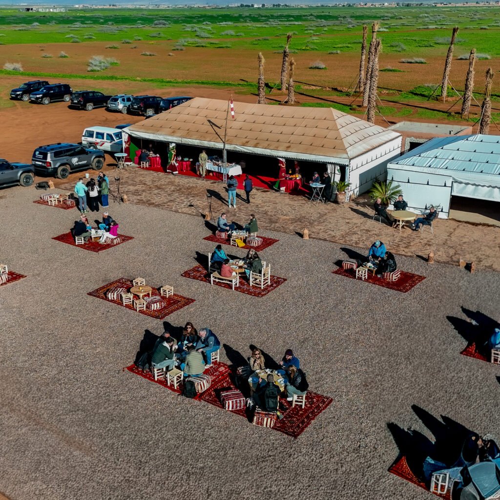 Aerial view of traditional Moroccan desert camp setup with Berber tents and outdoor seating on rugs