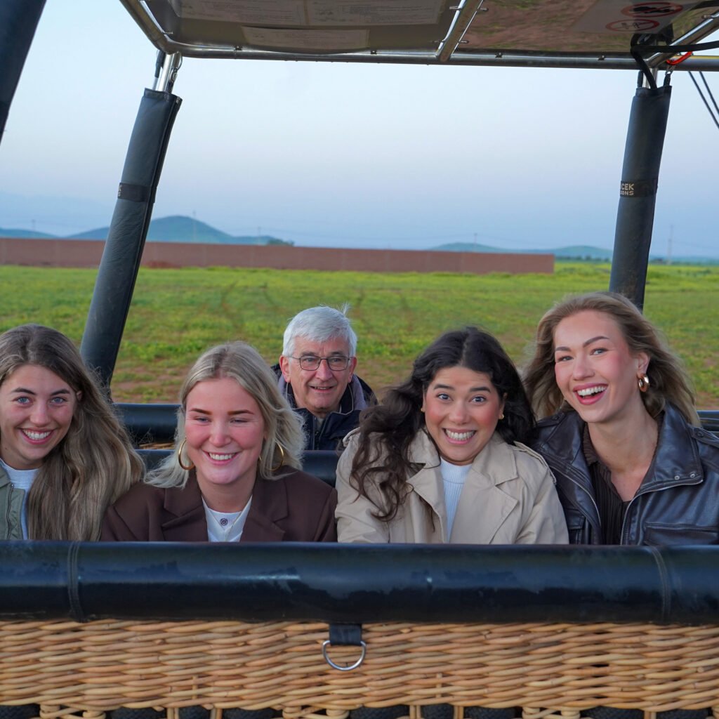 Group of happy tourists smiling inside a hot air balloon wicker basket before takeoff in Morocco