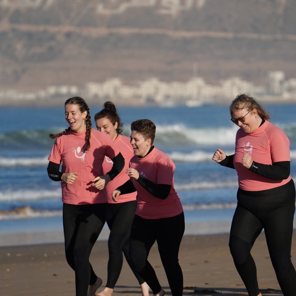 Group of female surfers running together along the sandy shore in Agadir