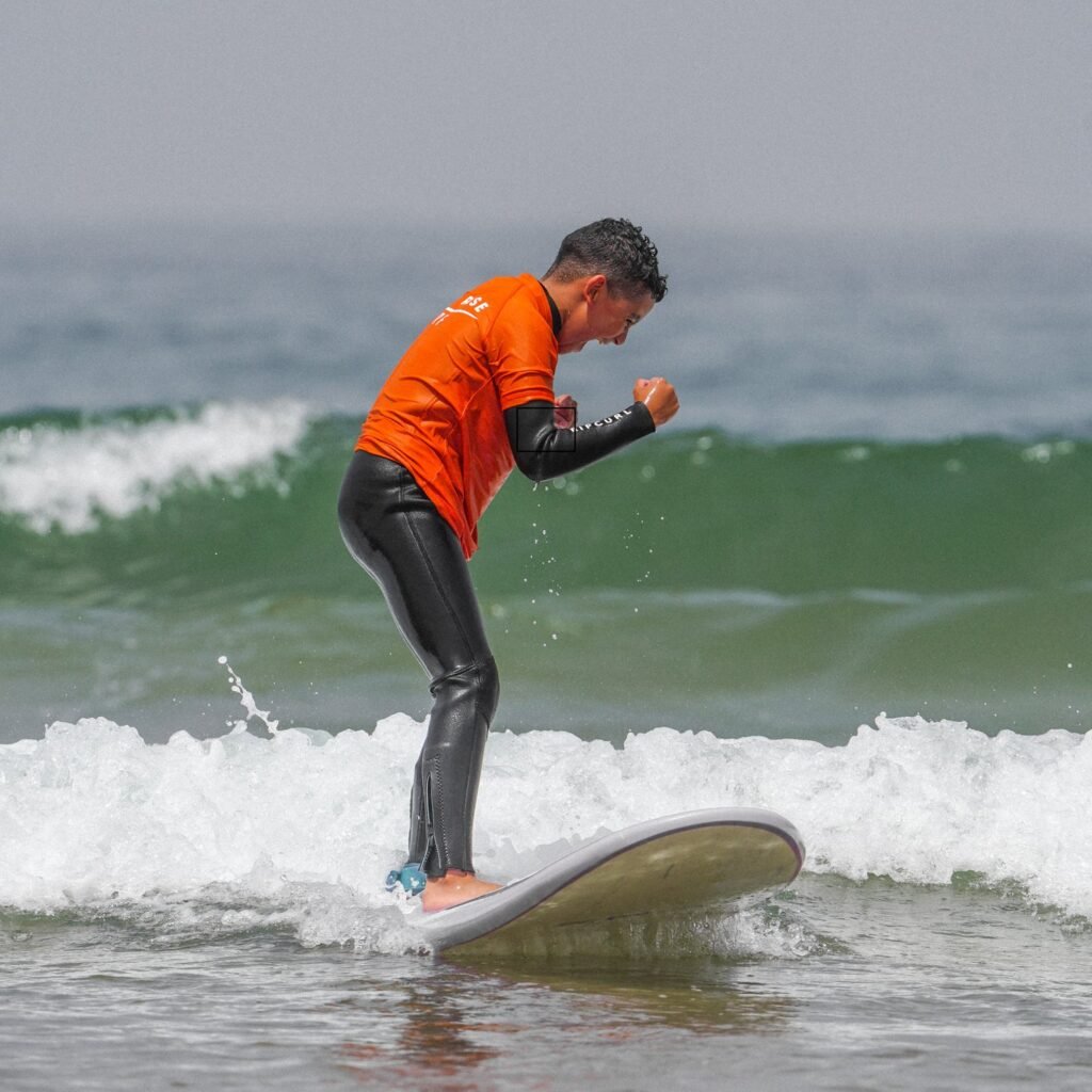 Young surfer celebrating with raised fists while balancing on a wave