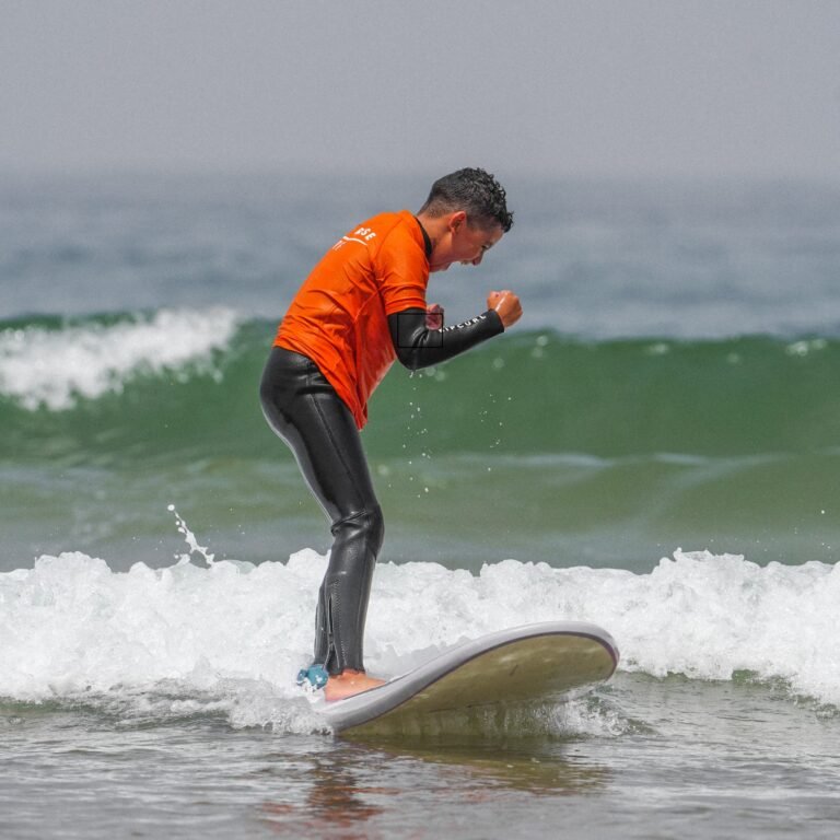 Young surfer celebrating with raised fists while balancing on a wave