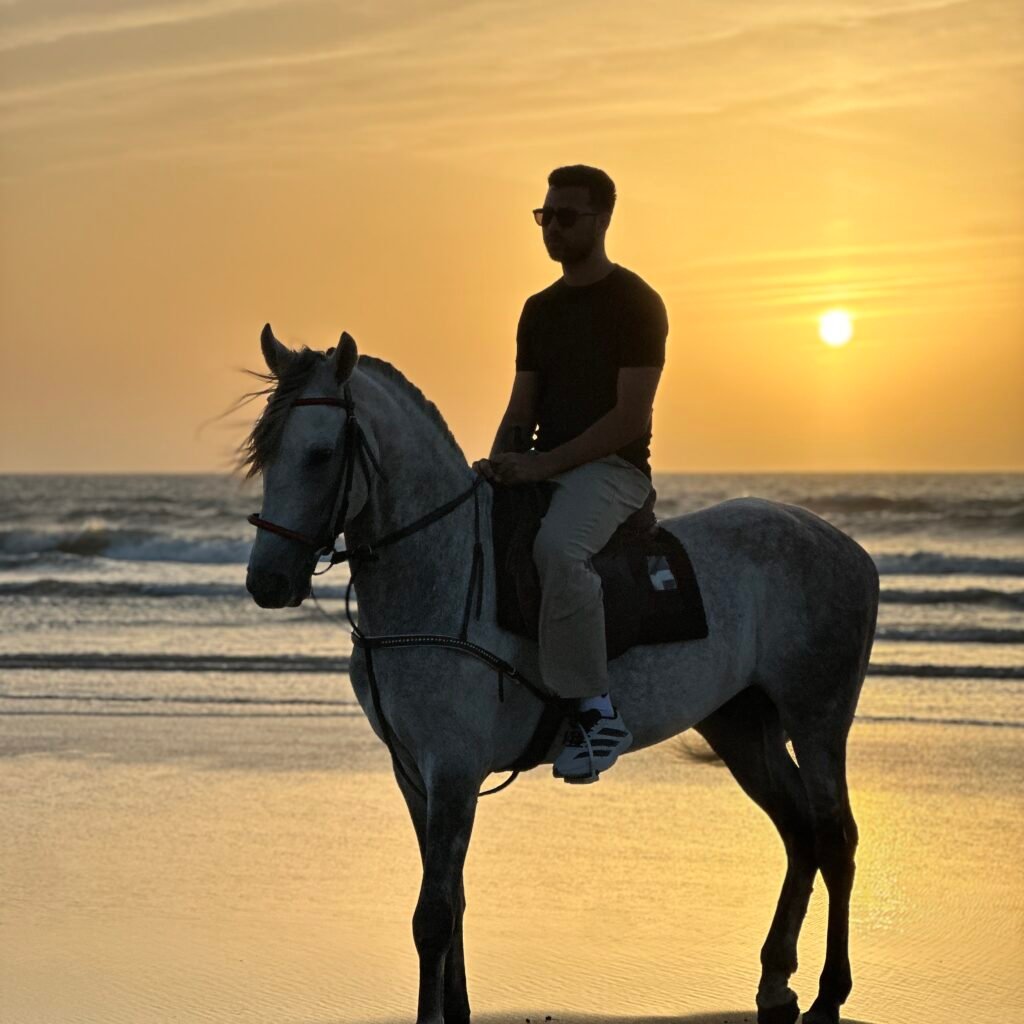 Silhouette of a male traveler on a white horse at sunset on