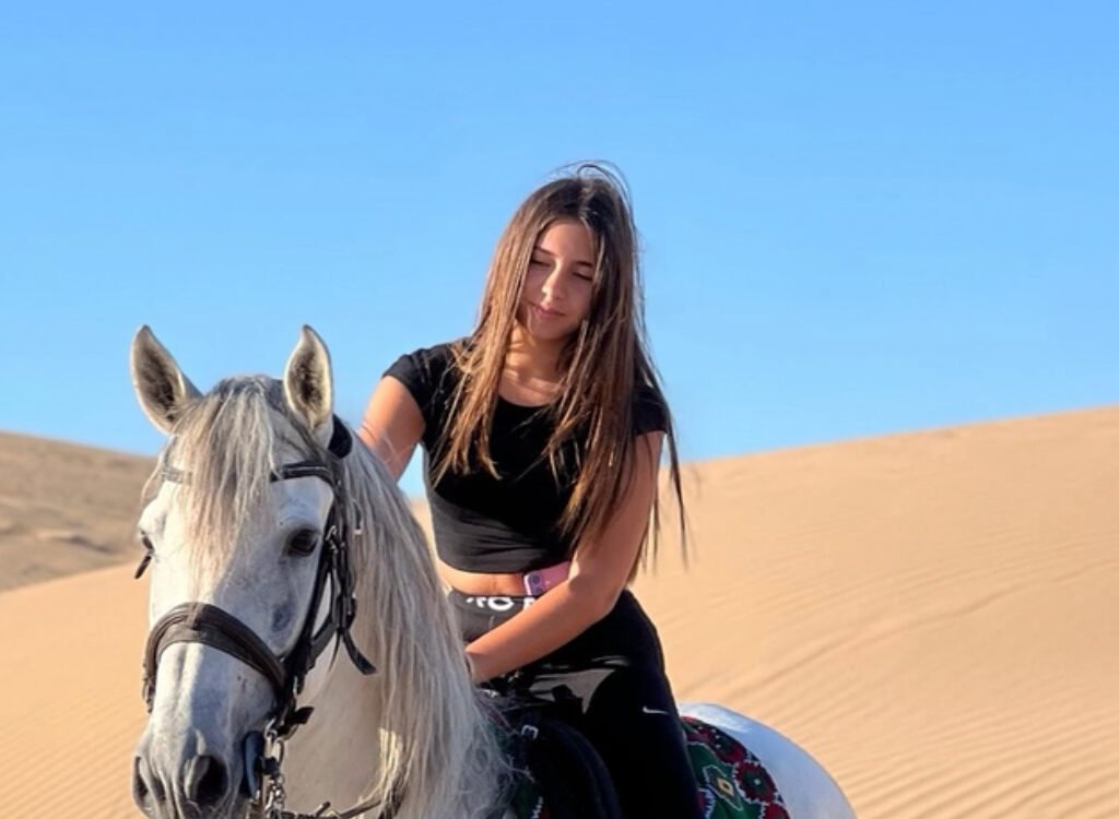 Young female traveler riding a white horse on desert sand dunes in Morocco