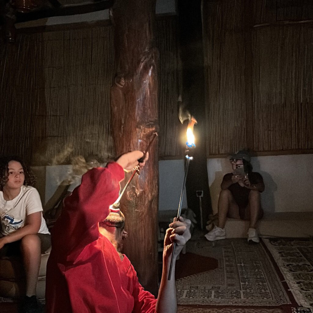 Performer executing a fire-spinning act with torches inside a traditional Moroccan dining hall