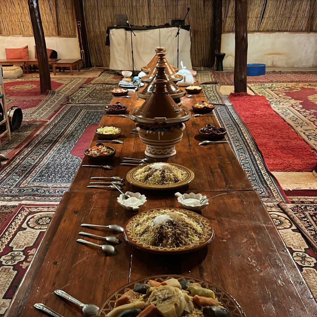 Long traditional dining setup with authentic Moroccan tagines, couscous dishes, and tableware