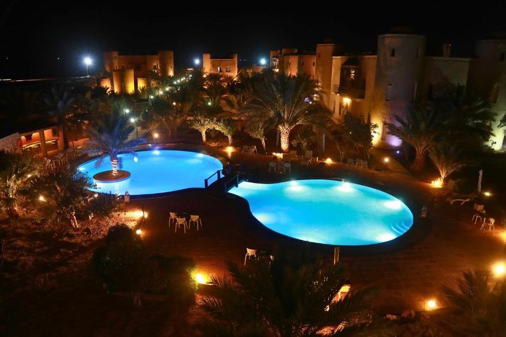 Illuminated outdoor swimming pools and palm trees at a Moroccan desert resort at night