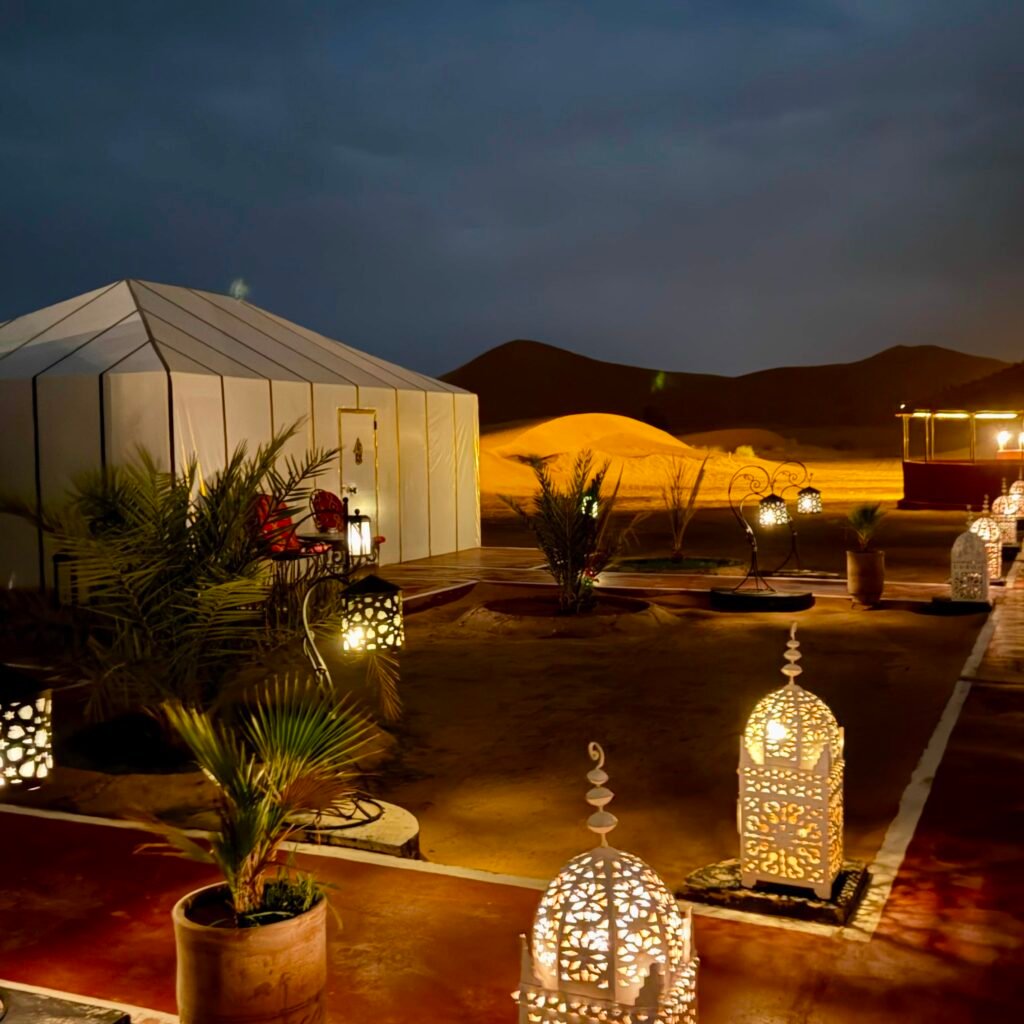 Traditional Moroccan metal lanterns lighting a pathway at a luxury desert tent camp at night