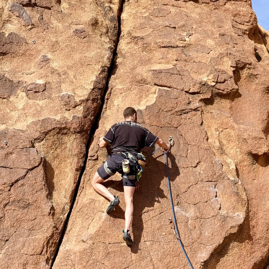 Climber walking past a massive suspended boulder formation in Tafraoute, Morocco